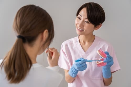 牙齒衛生員使用牙模為女性患者講解正確刷牙技巧，強調預防牙周病的重要性。
