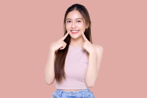 笑容自信的年輕女生展示整齊牙齒，代表傳統牙齒矯正（箍牙）治療效果｜香港牙齒矯正前後對比