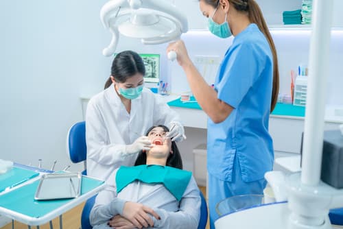 兩位牙科專業人員正在為女病人進行牙齒清潔與洗牙程序。